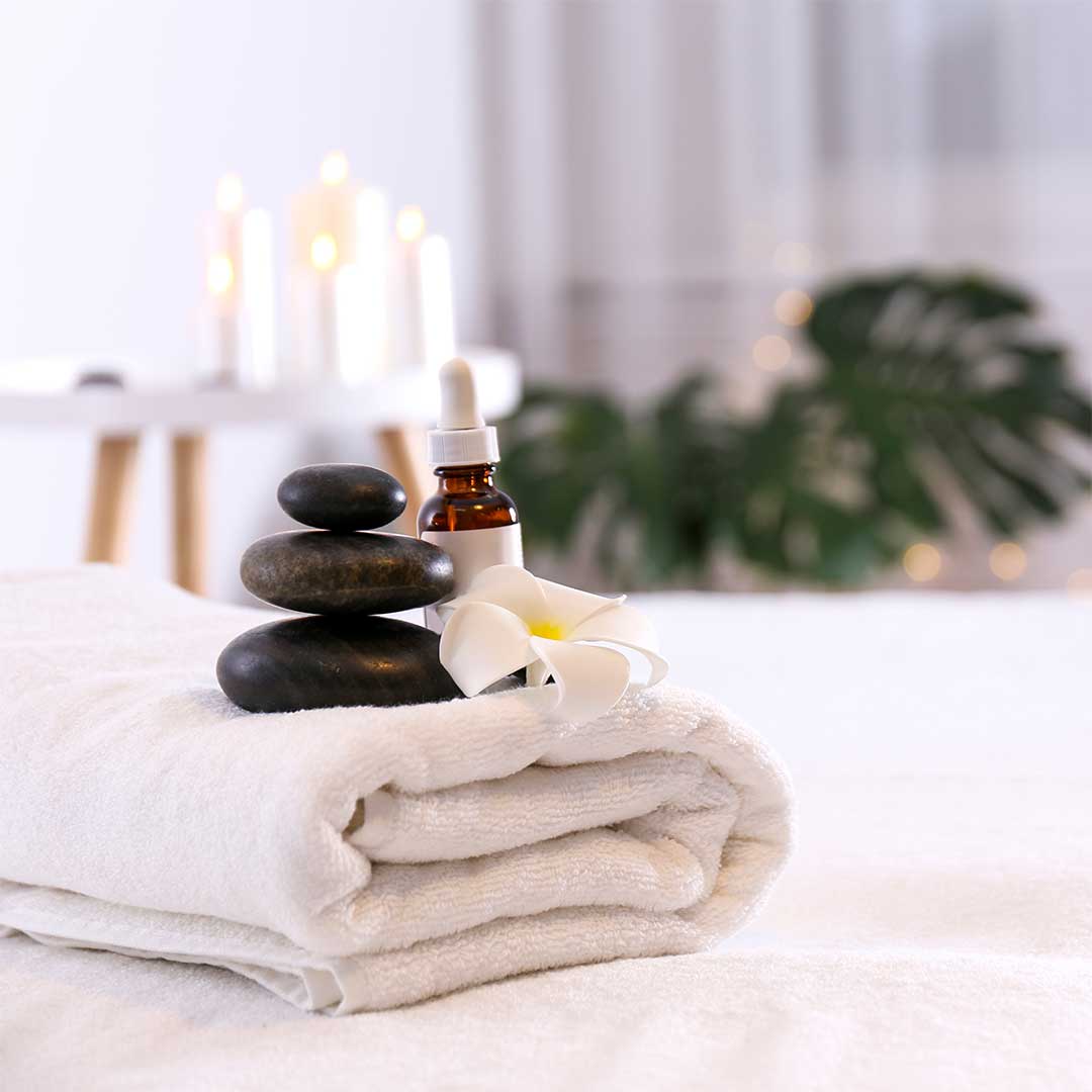 Massage table with towels, heating stones, and oils with candles